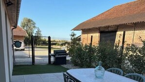 Un patio al aire libre con una mesa, sillas, una parrilla y una zona cubierta con pared de ladrillo y una reja metálica.