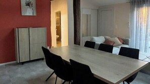 Un comedor con una mesa larga, sillas negras, una pared de acento roja y un tragaluz.