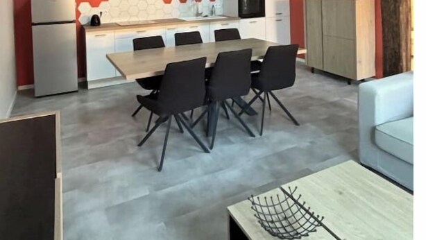 Una cocina moderna con comedor, que presenta vigas de madera a la vista, un tragaluz y una pared de acento roja.