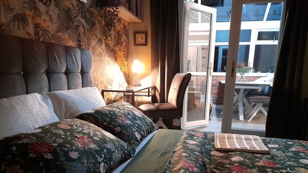 Une chambre à coucher avec un lit, une chaise, une lampe et une vue sur l’extérieur.