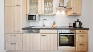 A compact kitchen with wooden cabinets, a built-in microwave, a gas stove, and a toaster. - Gorgeous apartment in Pörtschach am Wörtherse with lake view (Pörtschach am Wörtherse)