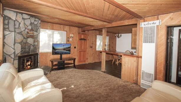 A cozy living room with a stone fireplace, a television, and a stone wall. - Cubs Nest (Sugarloaf)