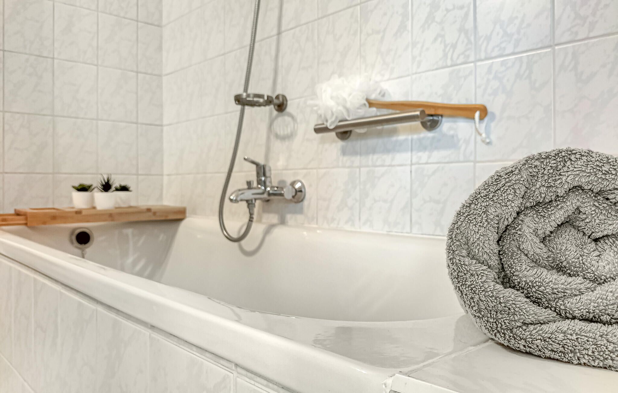 Een badkamer met een witte badkuip, een douchekop en een handdoekrek.