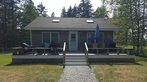 A house with a deck, a covered outdoor seating area, and a gravel path leading to the front door.