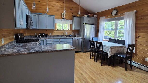 A modern kitchen with a central island, wooden floors, and a skylight.
