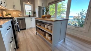 Eine moderne Küche mit weißen Schränken, Edelstahlgeräten und einer Holztheke mit Stauraum.