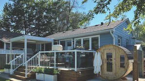 Ein Haus mit überdachter Terrasse, einer Holzterrasse und einer großen tonnenförmigen Struktur.
