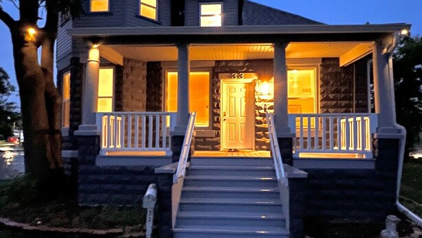 A two-story house with a stone facade, a wrap-around porch with white railings, and a front door with a number "33". - Comfy 4-bedroom house in Mount Clemens (Mount Clemens)