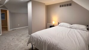 A bedroom with a single bed, a nightstand, and a wall-mounted light. - Comfy 4-bedroom house in Mount Clemens (Mount Clemens)