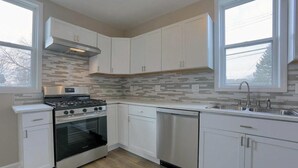 A modern kitchen with white cabinets, a stainless steel stove, and a dishwasher. - Comfy 4-bedroom house in Mount Clemens (Mount Clemens)