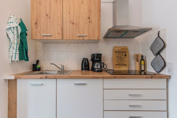 A kitchen with wooden cabinets, a stainless steel sink, a coffee maker, and a wooden sign on the countertop.
