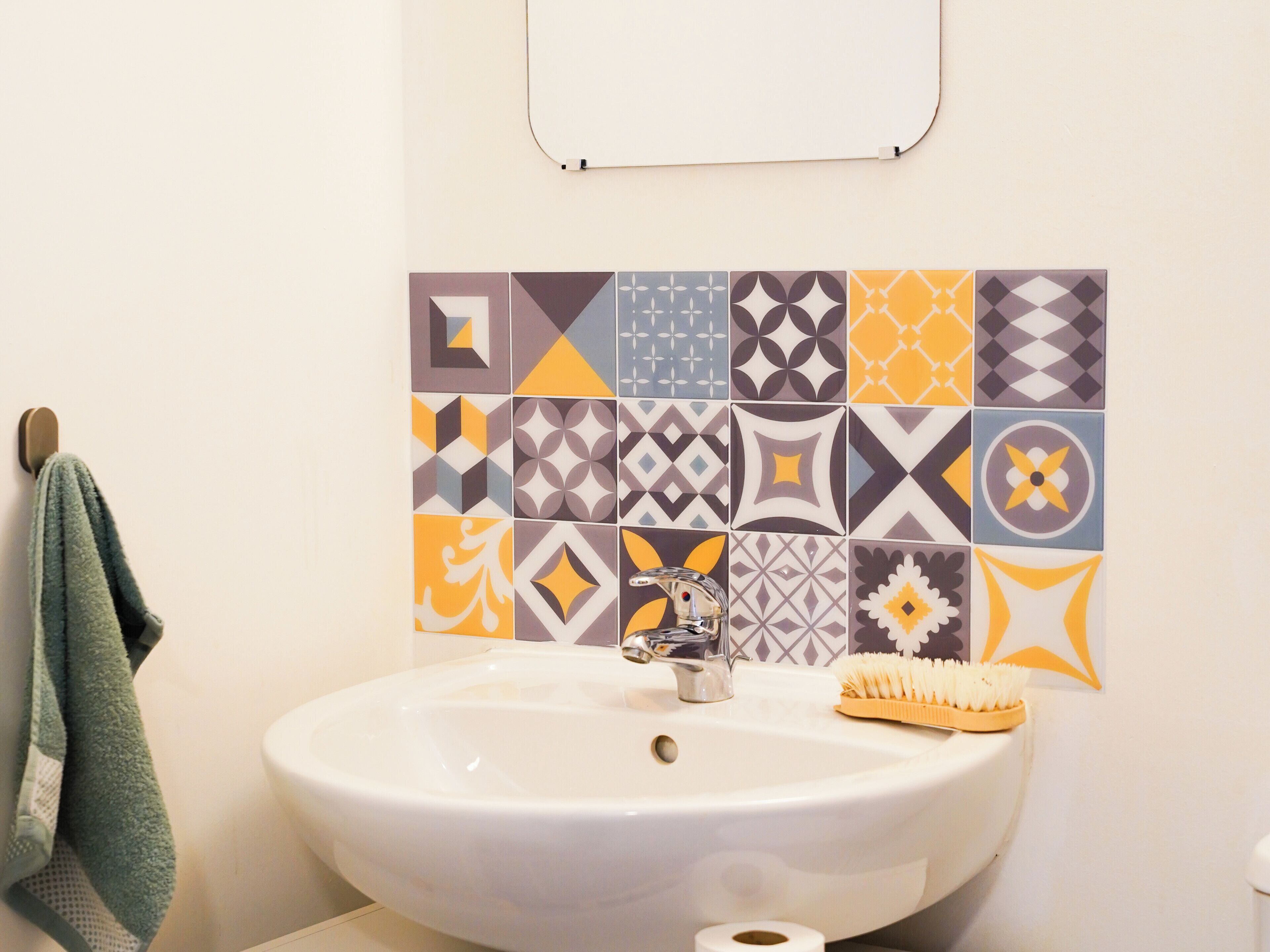 Un baño con un lavabo blanco, un espejo y un perchero para toallas.