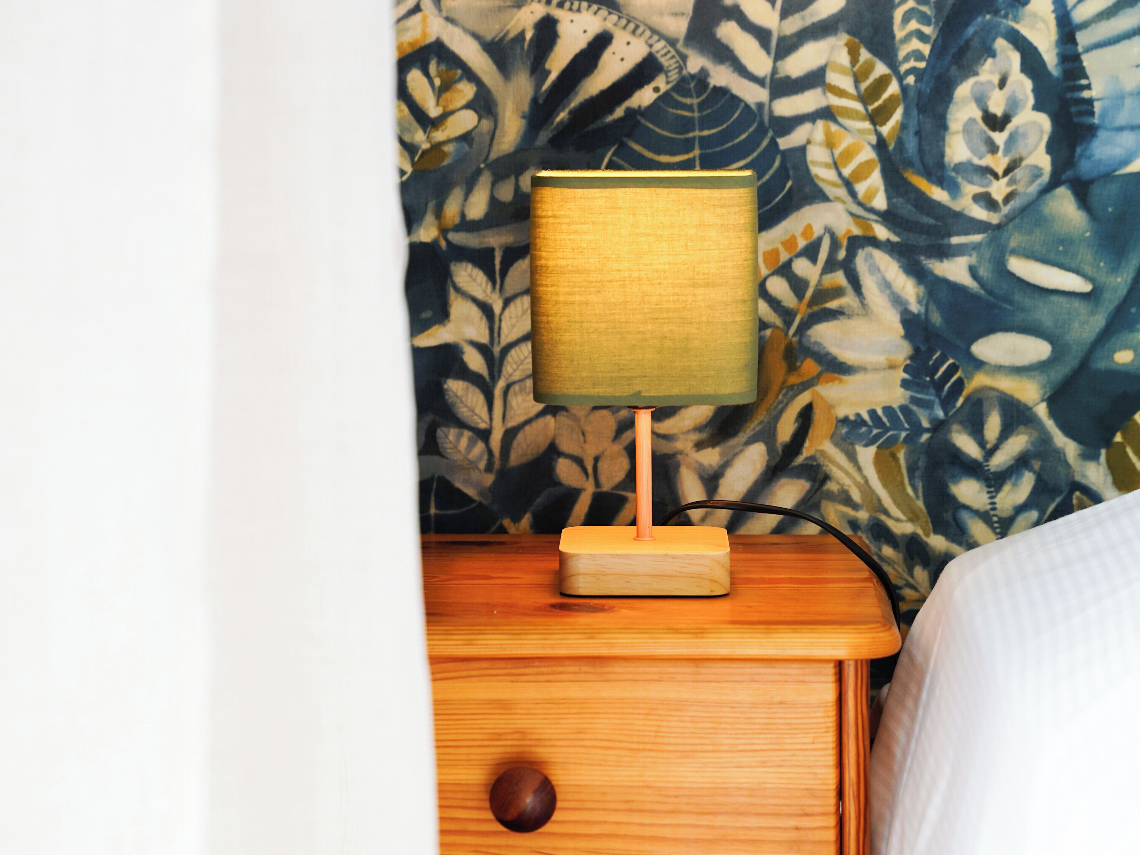 A wooden nightstand with a lamp and a drawer.