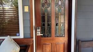 Uma porta de madeira com painel de vidro e desenhos detalhados, além de fechadura eletrônica.