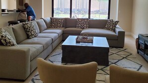 A living room with a sectional sofa, two armchairs, a coffee table, and a ceiling fan.