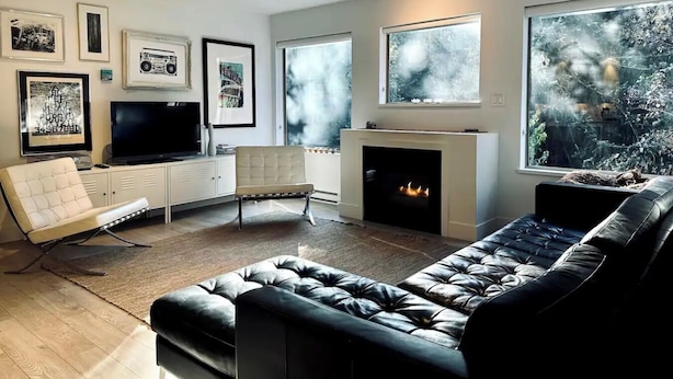A modern living room with a fireplace, a sofa, a TV, and framed pictures on the wall.