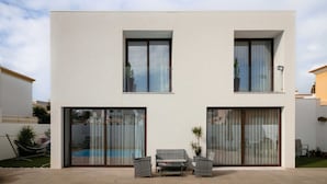 A modern two-story house with large sliding glass doors, a pool, and outdoor furniture. - Comfortable Villa Algarve for up to 10 guests (Alcantarilha)