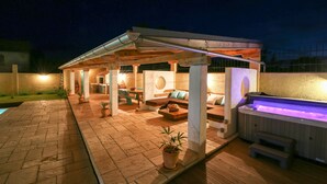 A covered outdoor patio with a hot tub, seating area, and a stone fireplace. - Amazing home in Gornje Rastane with sauna (Gornje Rastane)