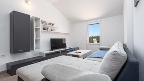 A modern living room with a sofa, a flat-screen TV, and built-in shelves. - Cozy apartment in Krusevo with WiFi (Krusevo)