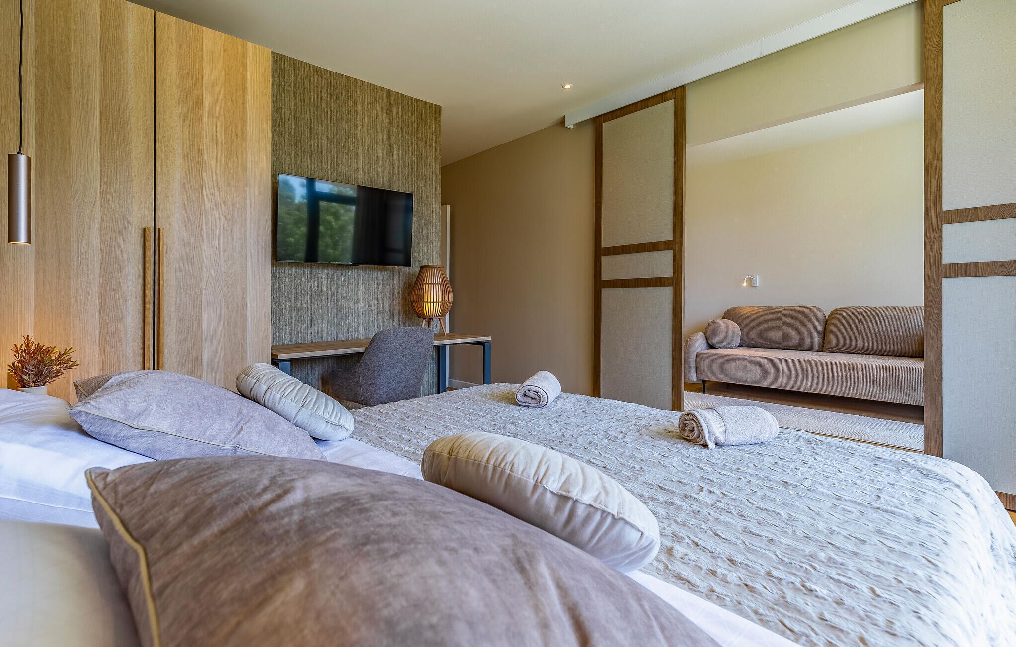 Una camera da letto moderna con un letto grande, una televisione, un divano e una porta scorrevole.