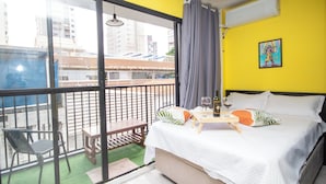 A hotel room with a balcony, a bed with pillows, a table with a bottle and glass, and a painting on the wall. - Maison Perdizes – Allianz Parque Supreme (Sao Paulo)
