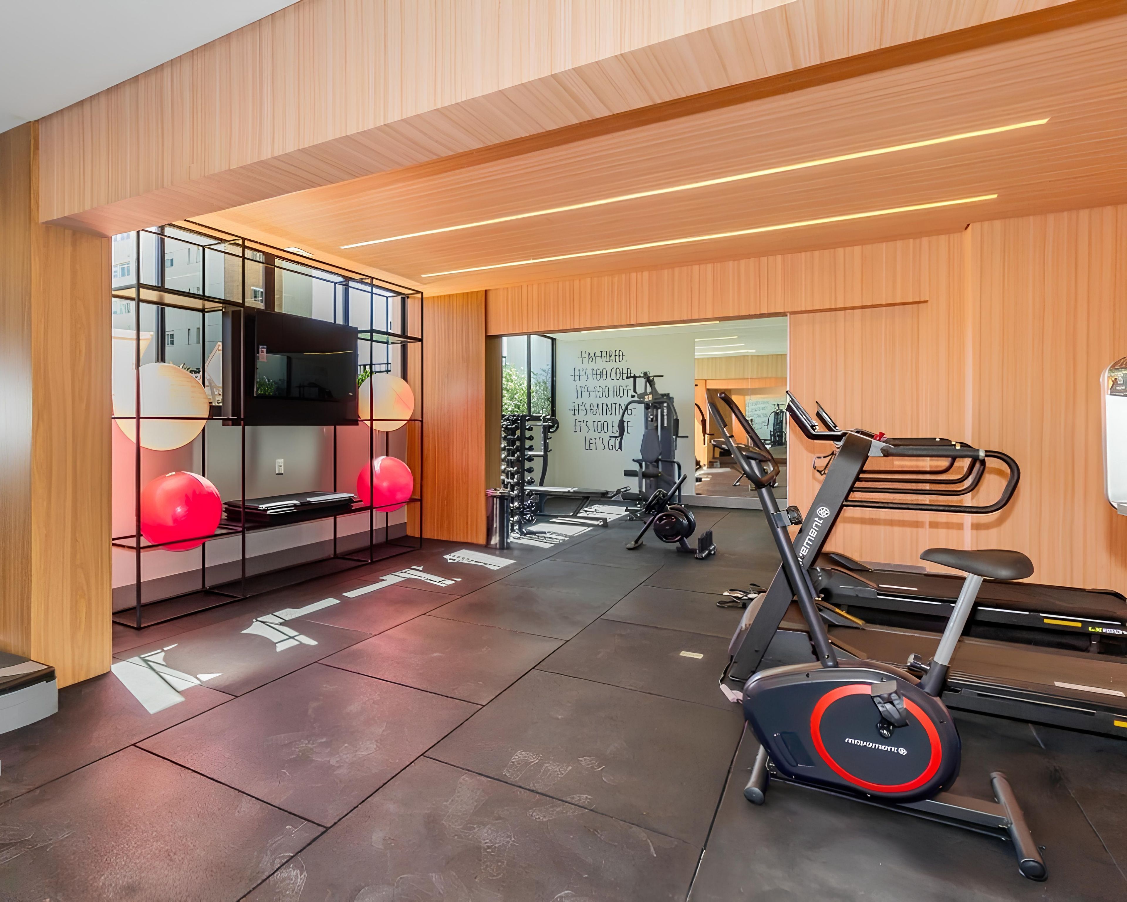 Un gimnasio moderno con equipo de ejercicio, una cinta de correr y un espejo grande.