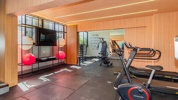 Un gimnasio moderno con equipo de ejercicio, una cinta de correr y un espejo grande.