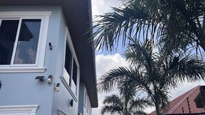 Edificio residenziale con facciata azzurra, modanature bianche e telecamera di sicurezza visibile.