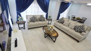 Uma sala de estar com dois sofás, uma mesa de centro e uma área de jantar com mesa e cadeiras.