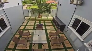 Ein Balkon mit Fliesenboden, einem Tisch mit Stühlen, einer kleinen Palme und zwei Wandklimaanlagen.