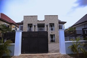 Un bâtiment à deux étages, doté d’une façade en pierre, d’un portail noir et d’une entrée pavée.