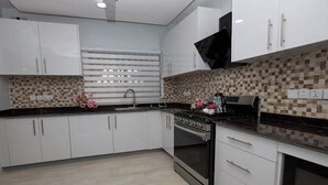 Una cocina moderna con armarios blancos, encimera negra y salpicadero de azulejos.