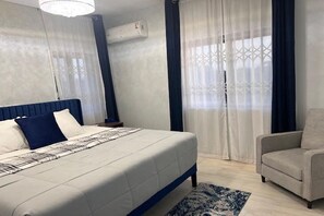 A bedroom with a bed, a chair, and a window with curtains.