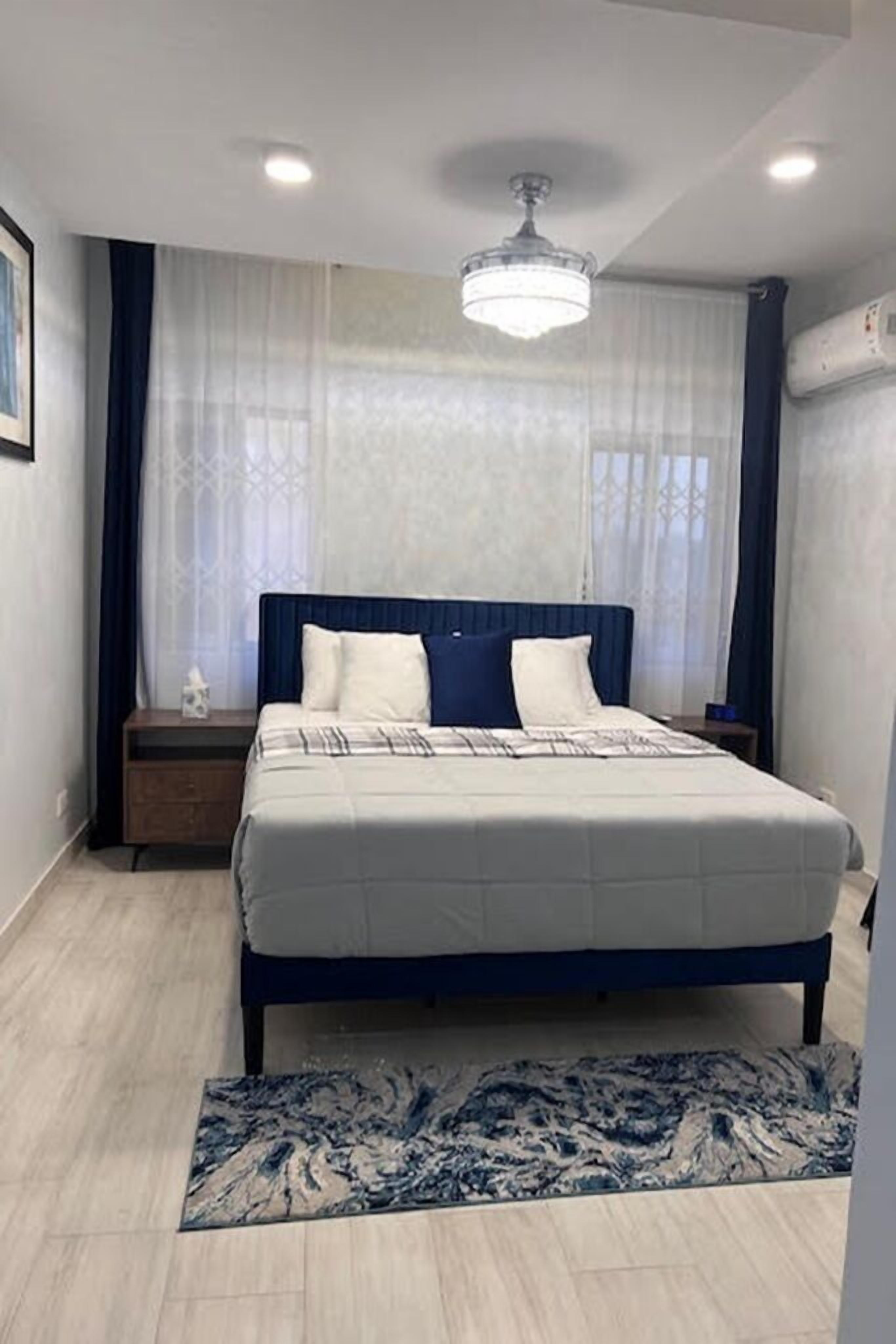 Camera da letto con un letto, comodini, un lampadario e un tappeto decorato.