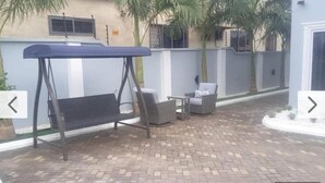 Un patio con una hamaca, una silla y una mesa.