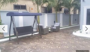 Une terrasse avec une balançoire, une chaise et une table.