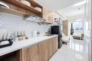 Une cuisine moderne avec des meubles en bois, un plan de travail blanc et un dosseret en carreaux hexagonaux.