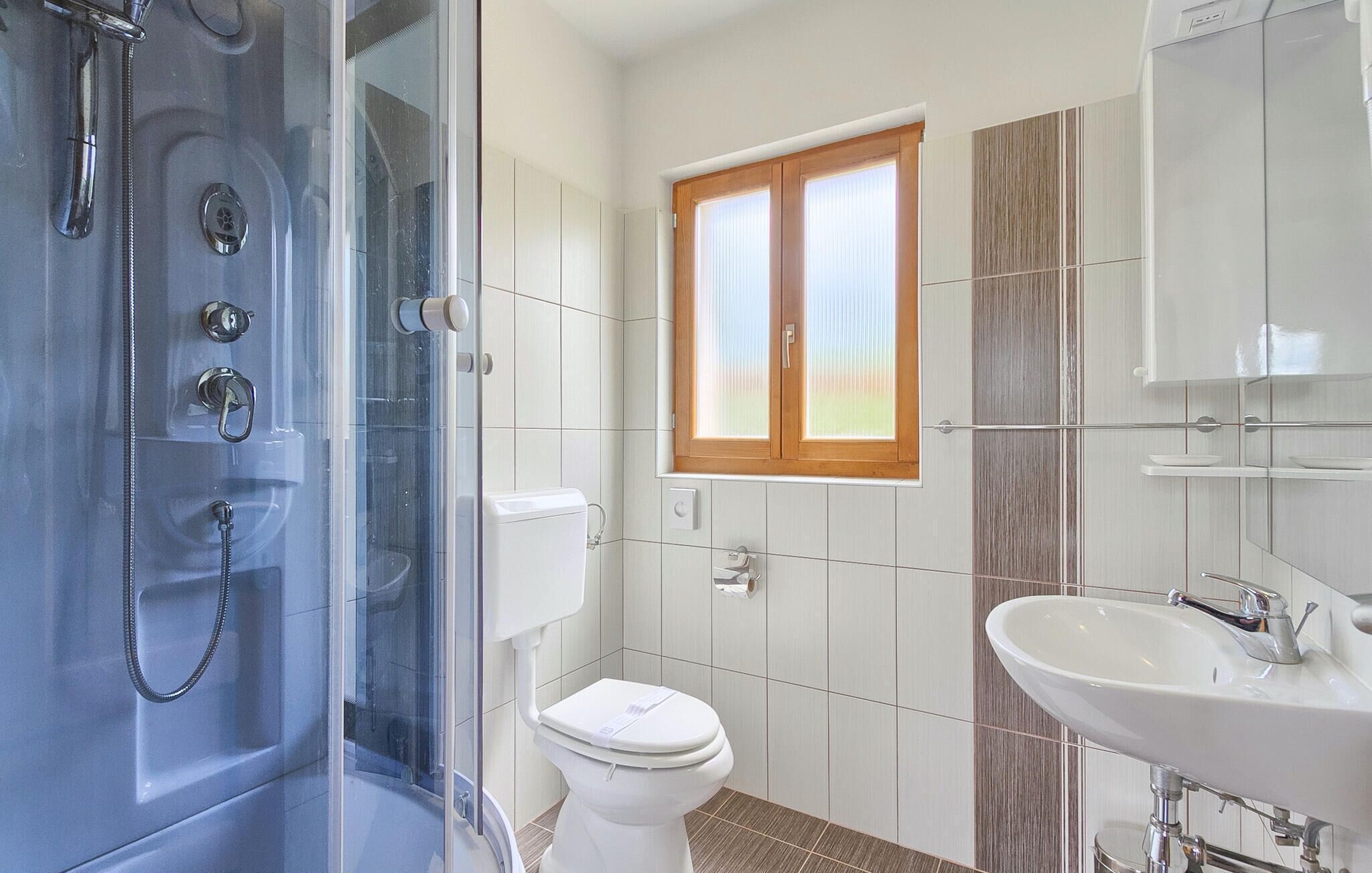 A modern bathroom with a glass-enclosed shower, a toilet, and a sink.