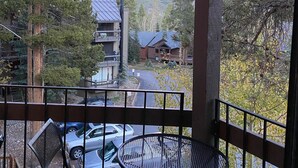 A balcony with a view of a mountainous landscape, a dining table, and chairs.