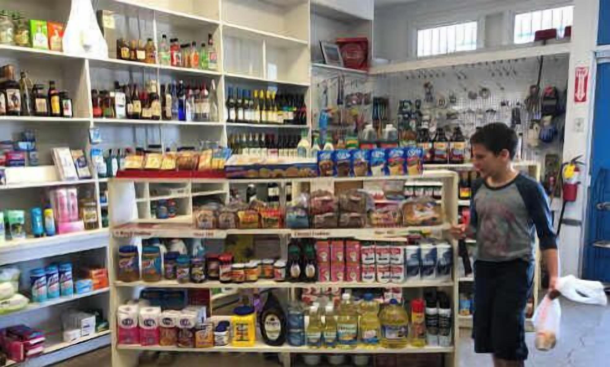 Una tienda con estantes llenos de diversos productos, como aperitivos, bebidas y artículos para el hogar.