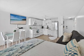 Un appartamento moderno con angolo cottura, zona pranzo e un letto con vista sulla spiaggia.
