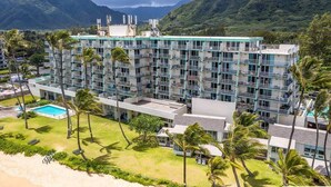 Un hôtel à plusieurs étages doté d’une piscine, entouré de palmiers et de montagnes.