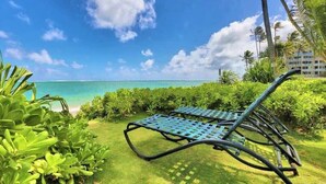Une vue sur la plage, avec des chaises longues et des plantes tropicales.