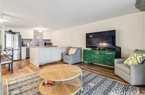 A modern kitchen with white cabinets, a built-in microwave, and a dining area with a round table and chairs.