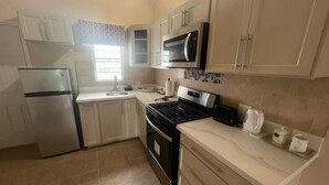 A compact kitchen with a refrigerator, stove, microwave, and a sink.