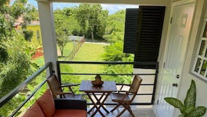 A balcony with a sofa, two chairs, a small table, and a potted plant.