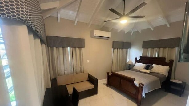A bedroom with a bed, a desk, a chair, and a ceiling fan.