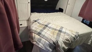 Une chambre à coucher de taille réduite, comprenant un lit, une armoire et une petite étagère.