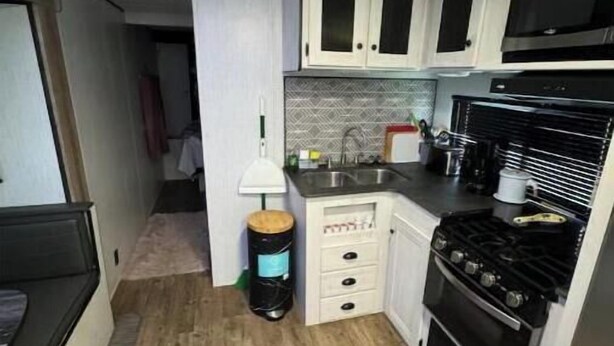 Une cuisine de taille réduite avec des meubles blancs, une cuisinière noire et un four à micro-ondes.