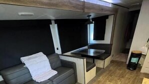 Un espace de vie compact comprenant un canapé, une petite table et un coin cuisine.